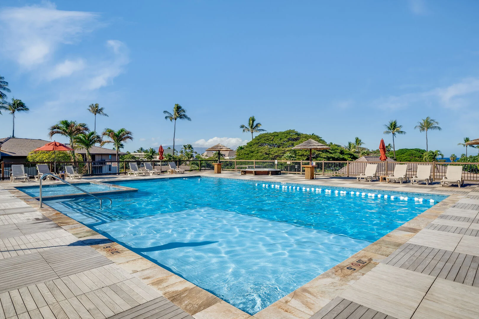 Maui Eldorado swimming pool with a paved deck, lounge chairs and palm trees